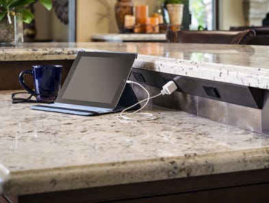 A tablet on a kitchen counter, plugged into a Task Lighting angle power strip.