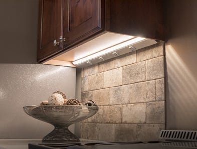 A Task Lighting lighted power strip hidden underneath a mounted wall cabinet.